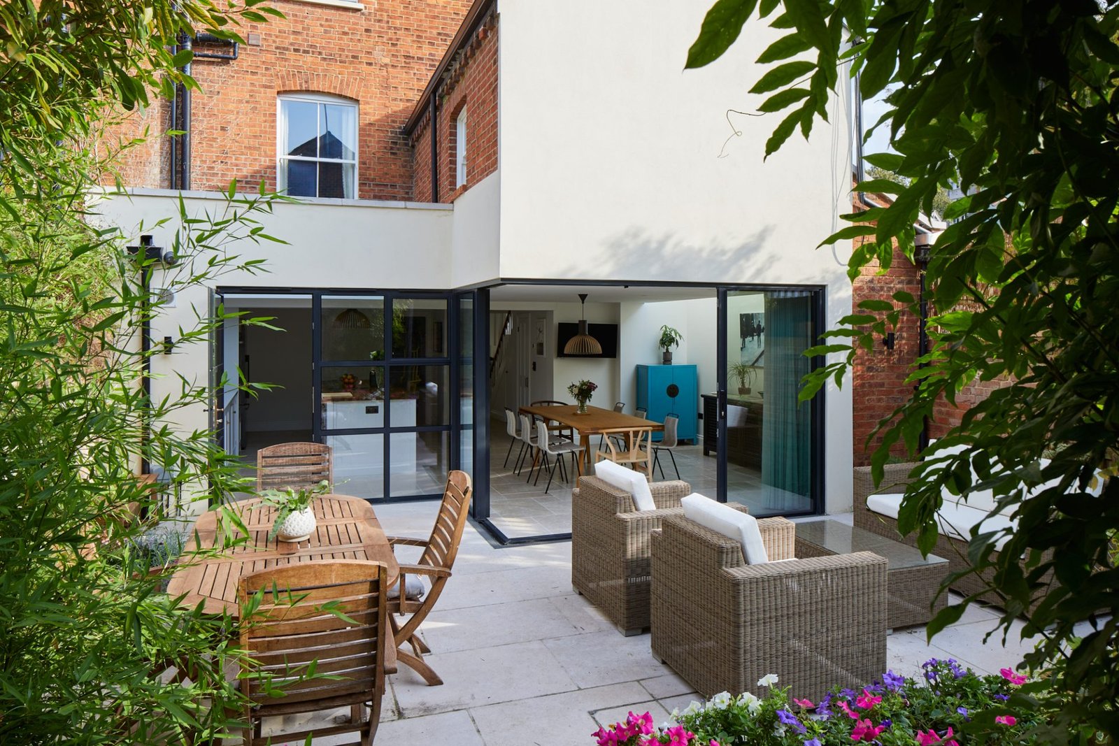 White rendered house with a glazed roof-lit extension and terrace at dusk